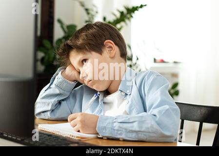 Apprentissage à distance pendant l'isolement pendant la quarantaine chez le coronovirus. Garçon et ordinateur portable à la maison. Style de vie. Banque D'Images