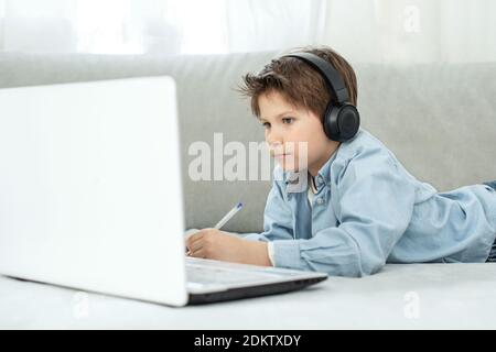 Apprentissage à distance pendant l'isolement pendant la quarantaine chez le coronovirus. Garçon et ordinateur portable à la maison. Style de vie. Banque D'Images