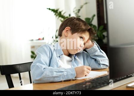 Apprentissage à distance pendant l'isolement pendant la quarantaine chez le coronovirus. Garçon et ordinateur portable à la maison. Style de vie. Banque D'Images