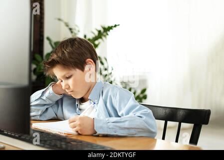 Apprentissage à distance pendant l'isolement pendant la quarantaine chez le coronovirus. Garçon et ordinateur portable à la maison. Style de vie. Banque D'Images