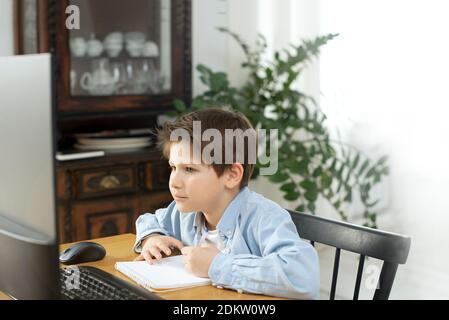 Apprentissage à distance pendant l'isolement pendant la quarantaine chez le coronovirus. Garçon et ordinateur portable à la maison. Style de vie. Banque D'Images