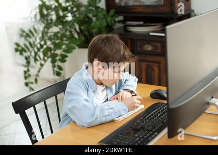 Apprentissage à distance pendant l'isolement pendant la quarantaine chez le coronovirus. Garçon et ordinateur portable à la maison. Style de vie. Banque D'Images