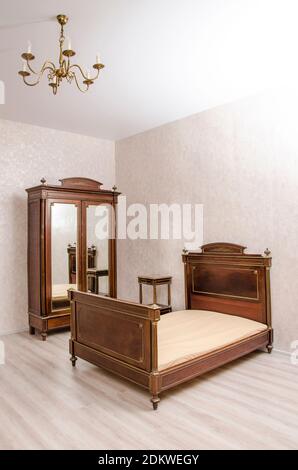 Antique vintage bedroom furniture: bed, bed table, wardrobe with mirror's doors and chandelier. Western Europe. Early 20th century Stock Photo