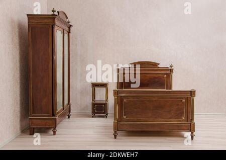 Antique vintage bedroom furniture: bed, bed table and wardrobe with mirror's doors. Western Europe. Early 20th century Stock Photo