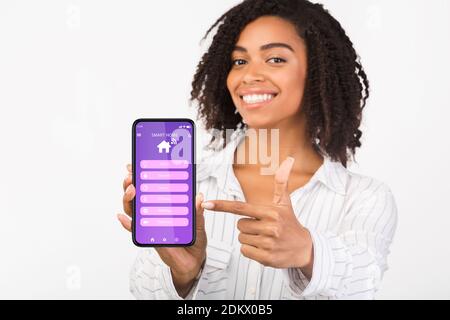 Collage de jeunes femmes noires contrôlant des appareils et des appareils, à l'aide de l'application Smart Home moderne sur un téléphone portable Banque D'Images