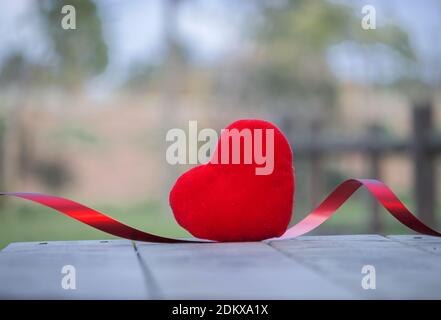 Coeur rouge sur bois rustique avec un long fil rouge dans un fond naturel. Concept de la Saint-Valentin 2021. Banque D'Images