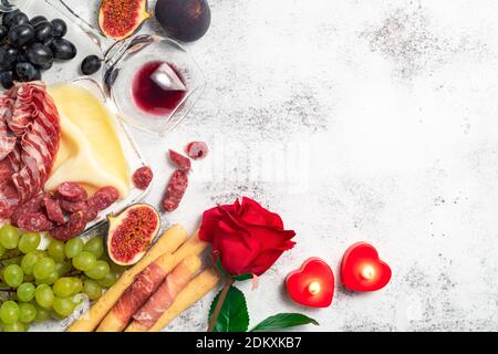 Saint-Valentin fond avec hors-d'œuvre sur table, en-cas italiens d'antipasti et vin. Raisin, figues, fromage, pain, prosciutto, musettes de viande. Antipasti, g Banque D'Images