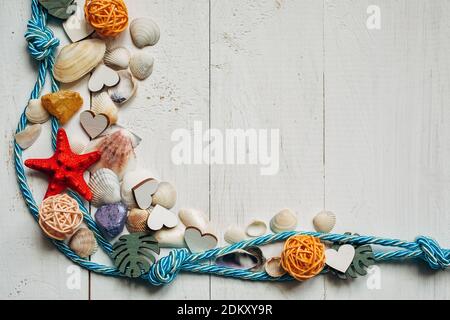 Lunettes de soleil, corde d'amarrage, coquillages et étoiles de mer rouges sur fond de bois blanc. Pli pour le texte. Banque D'Images