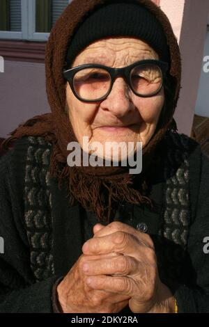 Comté de Vrancea, Roumanie. Portrait d'une femme âgée à l'extérieur de la maison par temps froid. Banque D'Images