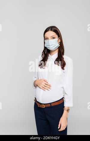 jeune femme d'affaires enceinte dans un masque médical isolé sur le gris Banque D'Images