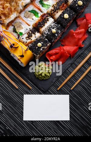 Assortiment de sushis sur fond de pierre. Carte blanche vierge pour le cercle d'inscription dont baguettes en bois . Banque D'Images