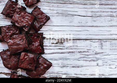 Squares of delicious, homemade fudgy brownies stacked a white rustic wooden table background. Image shot from top view overhead. Stock Photo