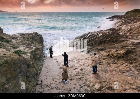 Lumière du soir comme quatre jeunes hommes se tiennent sur la plage dans une petite crique à Little Fistral à Newquay en Cornouailles. Banque D'Images