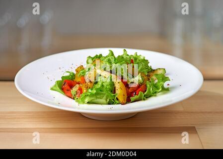 Salade de poivrons rouges et jaunes rôtis avec câpres et olives dans un bol bleu. Concept alimentaire sain sur fond de bois. Copier l'espace. Légumes grillés Banque D'Images