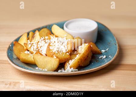 Des quartiers de pommes de terre frits sur l'assiette, de la sauce barbecue sur une surface en bois. Copier l'espace. Menu de bière au restaurant. Banque D'Images