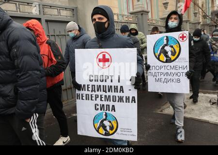 Non exclusif: KIEV, UKRAINE - 16 DÉCEMBRE 2020 - les jeunes hommes avec des pancartes en soutien aux travailleurs de la santé par les athlètes marchent dans une rue pendant le Th Banque D'Images