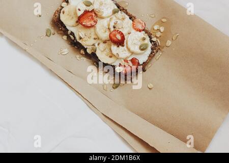 Toast nutritionnel à la crème saine pour le petit-déjeuner avec des fruits, du beurre d'arachide, du chanvre, de la citrouille, des graines de flux. Banane et fraise émaillées au miel Banque D'Images