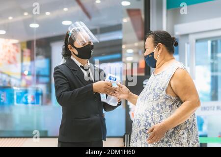 KANCHANABURI,THAÏLANDE-JUILLET 19,2020:les femmes de sécurité utilisent des thermomètres pour le corps et du gel d'alcool Service d'injection pour les clients afin de prévenir le coronavirus( Banque D'Images