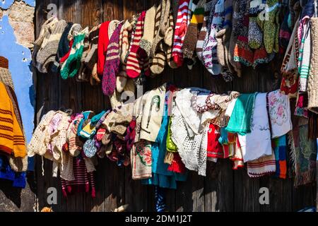 Handmade woolen knitted socks and clothes for sale designed by the locals, exhibited in front of their houses on a narrow street in Viscri, Romania, 2 Stock Photo