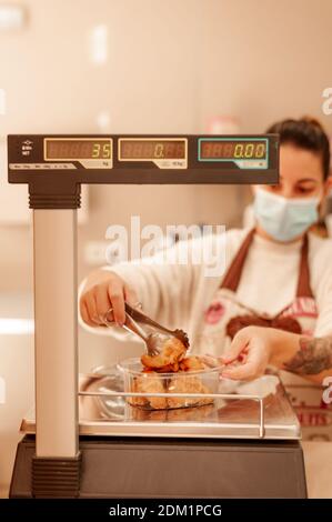 Propriétaire de boulangerie utilisant une balance portant un masque chirurgical. Nouveau concept normal. Banque D'Images