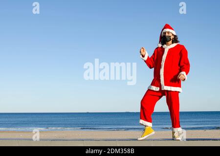 Une clause Santa avec un masque facial sur la plage Banque D'Images