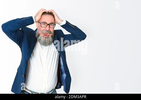 Un gars hystérique avec ses mains sur sa tête et criant. Homme barbu dans une élégante veste bleue et des lunettes se posant isolé sur fond blanc. Annoyan Banque D'Images