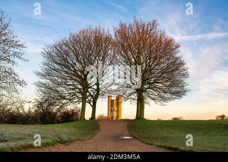 Broadway Tower à travers les arbres au lever du soleil en hiver le long de la cotswold Way. Broadway, Cotswolds, Worcestershire, Angleterre Banque D'Images