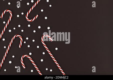 Cannes de Noël à rayures entourées de boules de neige blanches arrière-plan sombre avec espace de copie vide sur le côté Banque D'Images