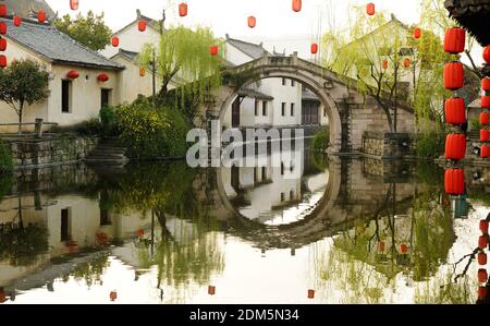 Village typique chinois avec pont de pierre sur l'eau calme. Banque D'Images