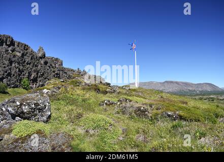 Un mât battant pavillon islandais se dresse au milieu des falaises de basalte dans le parc national de Thingvellir, sur le site du premier Parlement du pays. Banque D'Images