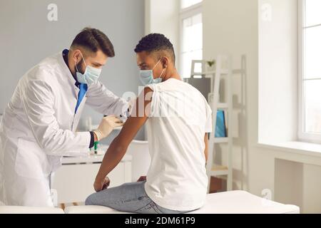 Jeune homme noir se fait vacciner contre le COVID-19 par un médecin Banque D'Images