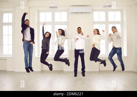 Groupe de collègues ou d'amis heureux et énergiques qui sautent tous ensemble et célébrer le succès Banque D'Images