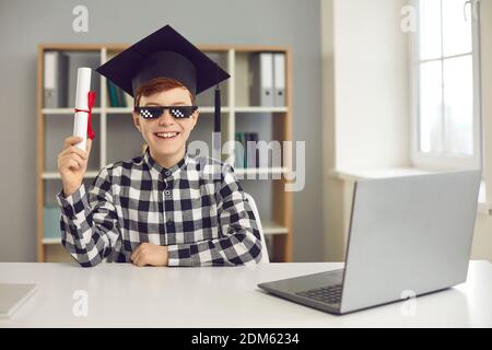 Un bon étudiant assis au bureau avec un ordinateur portable et un cours de tenue certificat d'achèvement Banque D'Images