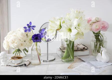 Un bouquet de roses blanches dans un vase en verre rond, un bouquet d'amaryllis blanc, une tasse de thé, une figurine sur la table. Décoration de la cuisine. Rose P Banque D'Images