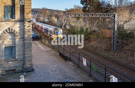 Un train sur la ligne Airedale du train Nord à Saltaire, dans le Yorkshire. La ligne longe Salts Mill. Banque D'Images