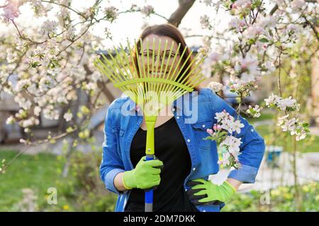 Jardinage de printemps, portrait d'une femme mûre souriante avec râteau regardant l'appareil photo Banque D'Images