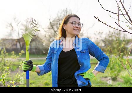 Jardinage de printemps, portrait de femme mûre souriante jardinier avec râteau Banque D'Images