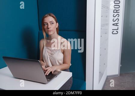 Jolie jeune femme travaillant sur son ordinateur portable à l'université moderne Banque D'Images