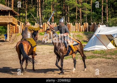 Cedynia, Poland June 2019 Historical reenactment of Battle of Cedynia, duel or sword fight, between two knights on horses in front of the wooden fort Stock Photo