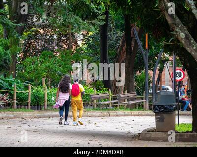 MEDELLIN, COLOMBIE - 03 décembre 2020: Medellin, Antioquia, Colombie - 2 décembre 2020: Enfants marchant dans le parc avec des feuilles d'arbres secs Banque D'Images