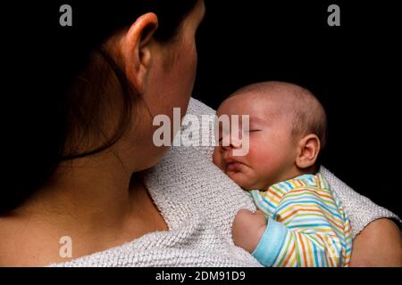 Bébé mignon dormant dans les bras de mère Banque D'Images