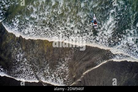 Vue de drone de la personne kayak dans les vagues de mousse de l'océan Roulant sur la côte de l'Islande Banque D'Images