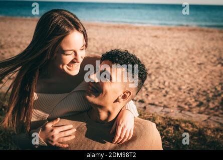 Un jeune couple amoureux se embrassant et souriant sur la plage Banque D'Images