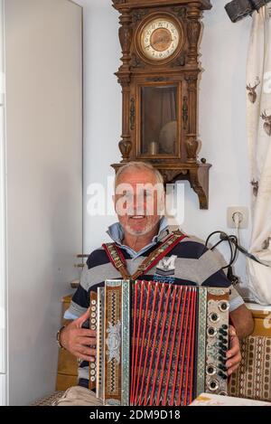 L'homme joue l'Accordéon de Styrie dans un ancien parlor de ferme Banque D'Images