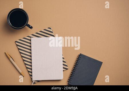 Table de bureau élégante avec tasse de café, carnets en papier et stylo sur fond marron pastel. Flat Lay, vue de dessus élégant espace de travail féminin. Bus Banque D'Images