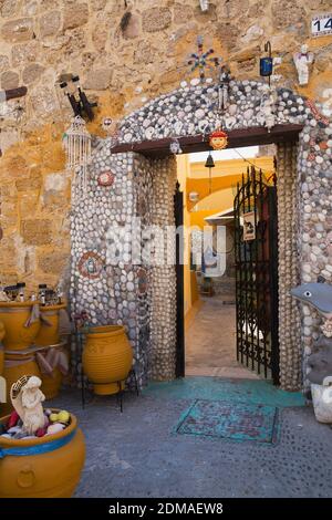 Bâtiment commercial avec porte d'entrée en fer forgé noir entouré de murs incrustés de galets et de pierres et de décorations sur le thème du poisson. Banque D'Images