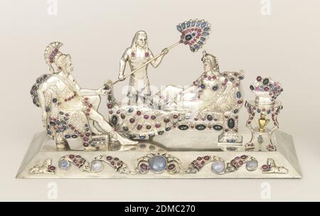 Groupe sculptural, argent coulé, diamants, rubis, saphirs, argent coulé, nappe incrustée de bijoux montrant le soldat romain en pleine régalia assis en face de la femme égyptienne couché sur un canapé, et bronzé par un serviteur debout; petite table de trépied à droite du canapé, tenant un bol de fruits ou de fleurs et l'urne sur l'étagère en dessous. Tous sur plinthe rectangulaire., Autriche, Allemagne, fin du XIXe siècle, travail de métaux, Arts décoratifs, groupe sculptural Banque D'Images