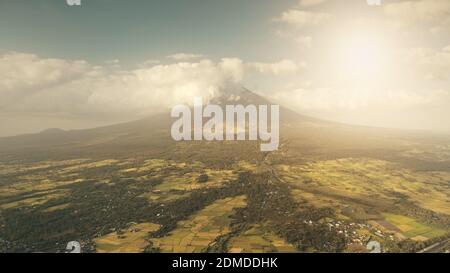 Terres de campagne de soleil tropique à flanc de colline verte volcan de l'antenne de vallée. Campagne de Legazpi aux Philippines tropicales. Attraction touristique de Mayon Mount Erupt. Les nuages hantent l'éruption au sommet de la montagne à la lumière du soleil Banque D'Images