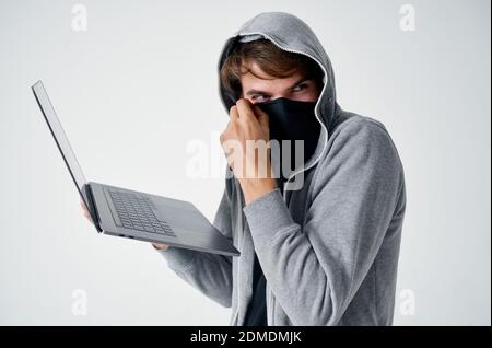 homme dans le noir gris avec ordinateur portable masque caché piratage ordinateur Banque D'Images