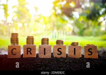 Crise économique et financière récession et dépression concept. Diminution de la pile de pièces de monnaie sur des blocs de bois au coucher du soleil. Banque D'Images